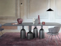 Tavolo Cop con piano in ceramica e base in metallo formata da elementi stilizzati ispirati a bottiglie, calici preziosi e coppe di champagne di Bonaldo